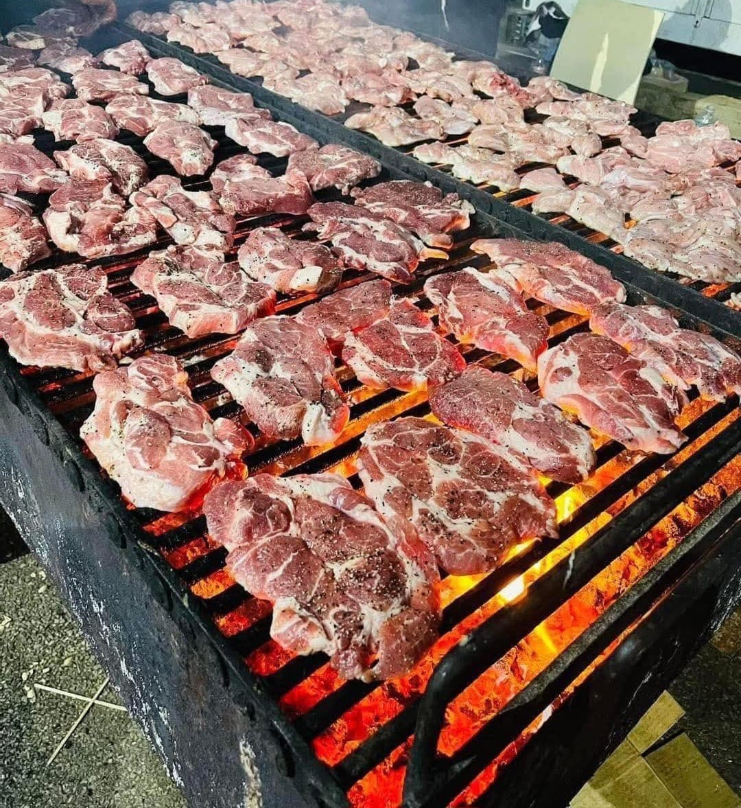 Meats cooking over a large charcoal grill