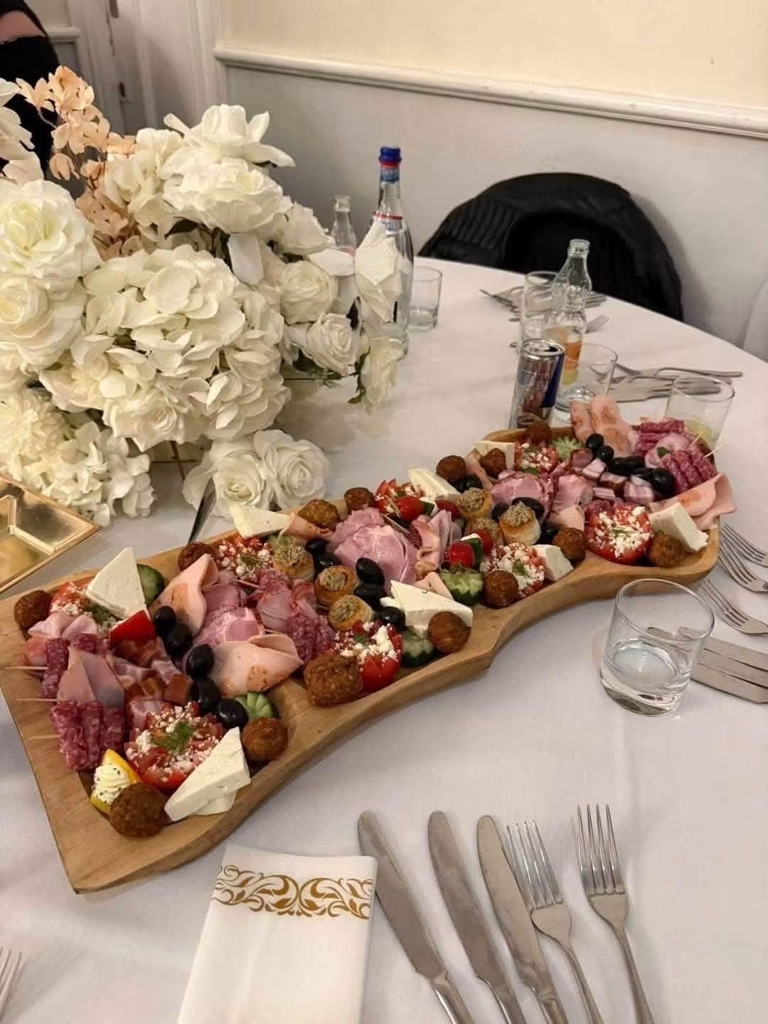 Wooden sharing board of food on a wedding table decorated with white flowers